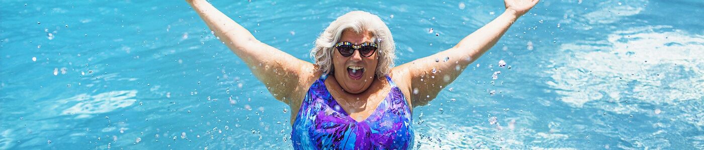 senior woman jumping out of water in pool